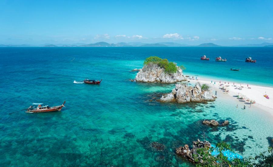 Spiaggia tropicale con acque cristalline e barche tradizionali nella baia di Phang Nga