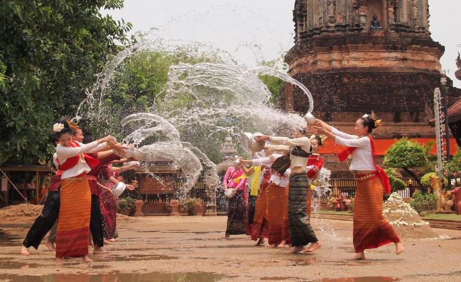 Donne thailandesi celebrano il festival Songkran con schizzi d'acqua davanti a un tempio antico