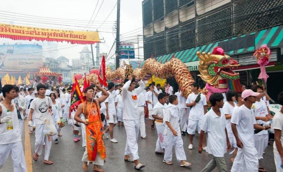Una folla di persone vestite di bianco in corteo durante il Festival Vegetariano di Phuket.