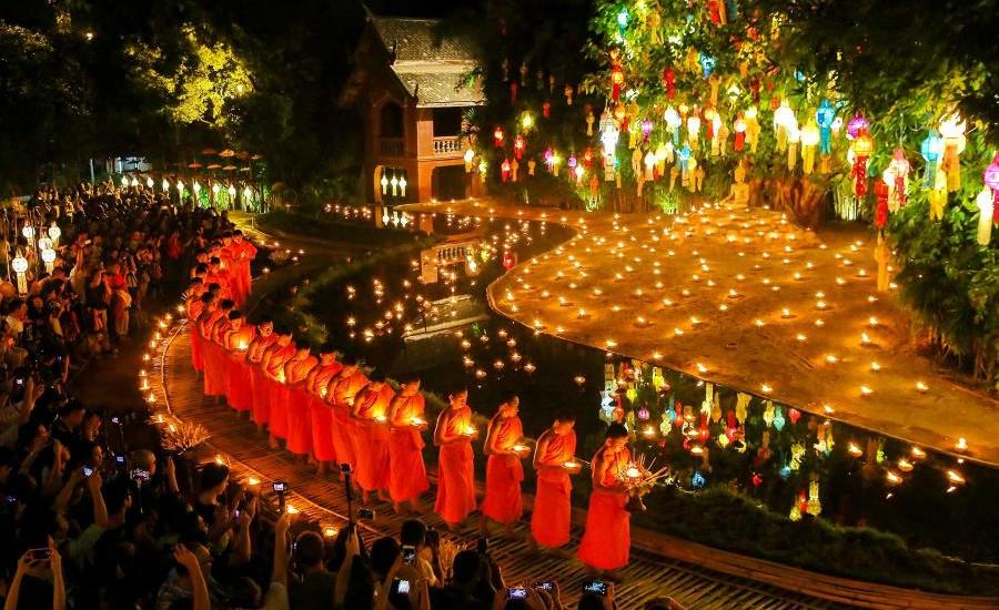 Monaci buddisti accendono candele tradizionali attorno allo stagno durante il festival Loy Krathong in Thailandia