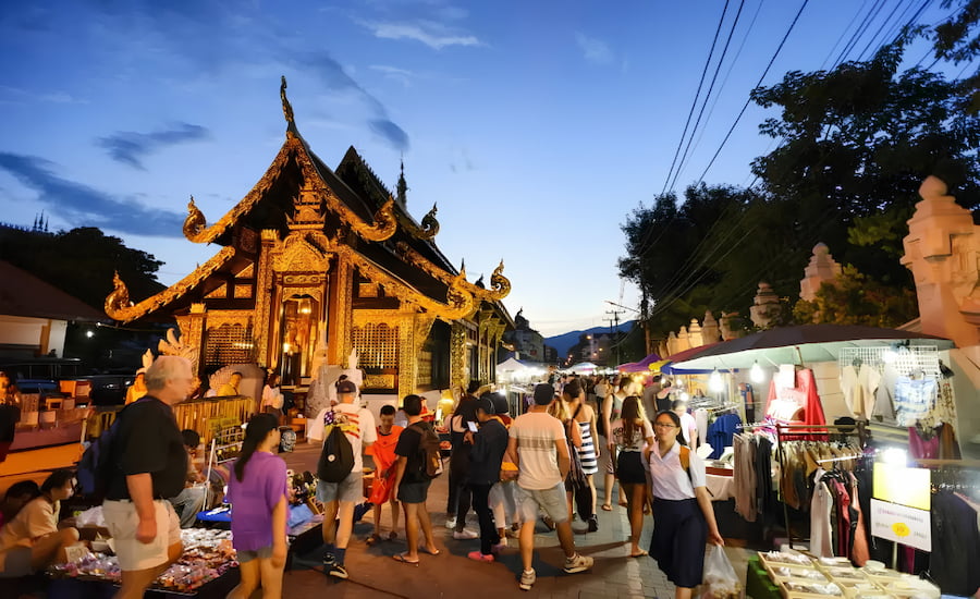 Bancarelle illuminate e folla di turisti al mercato notturno di Chiang Mai