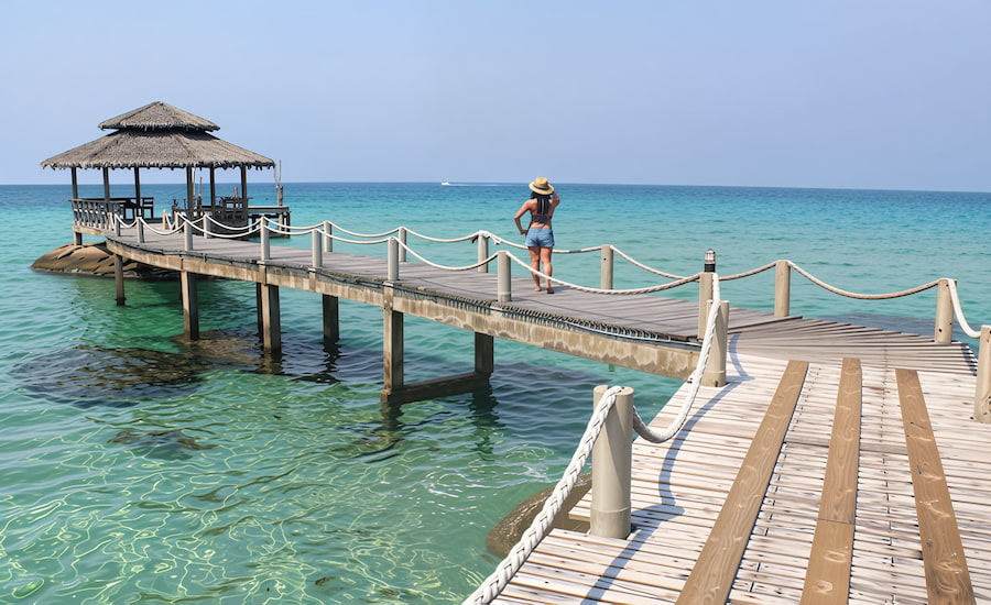 Una ragazza che ammira il mare cristallino da un pittoresco molo di legno