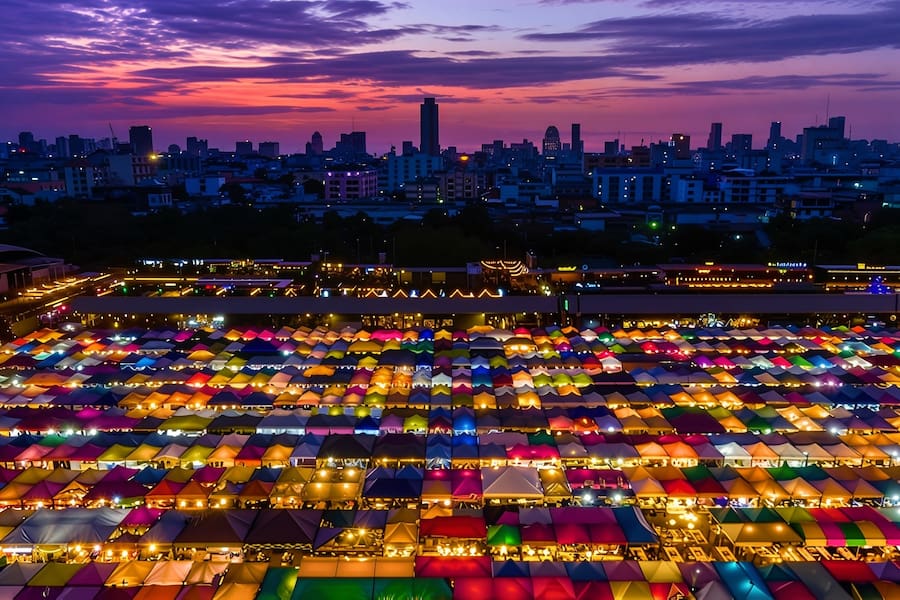 Turisti che fanno acquisti tra le colorate bancarelle del mercato di Chatuchak
