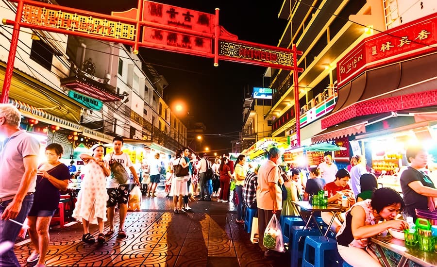 Insegne luminose al neon e vivaci bancarelle di cibo di strada a Chinatown Bangkok