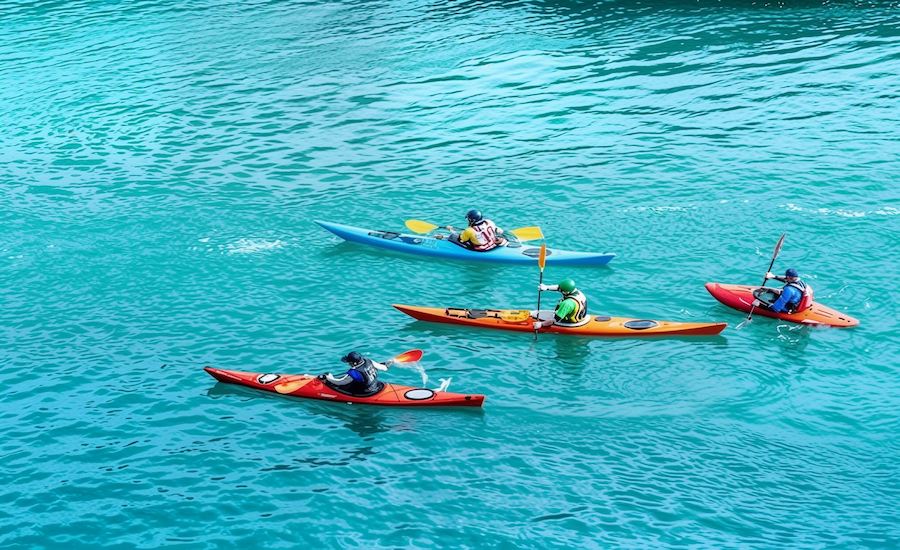 Turista che pratica kayak nelle acque cristalline e tra le scogliere di Koh Yao Noi