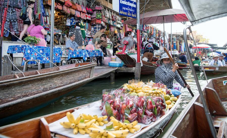 Barche tradizionali cariche di frutta fresca al mercato galleggiante in Thailandia