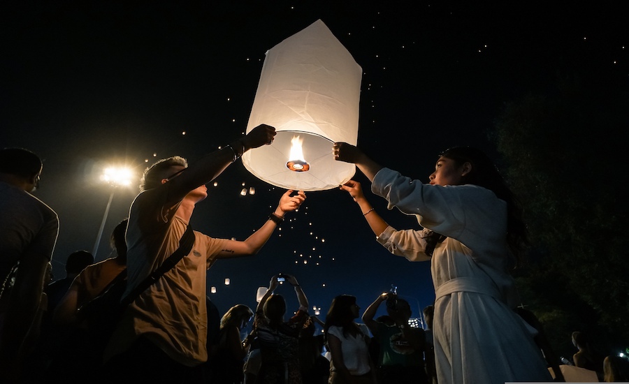 Persone che accendono e sollevano una lanterna di carta durante il festival di Chiang Mai