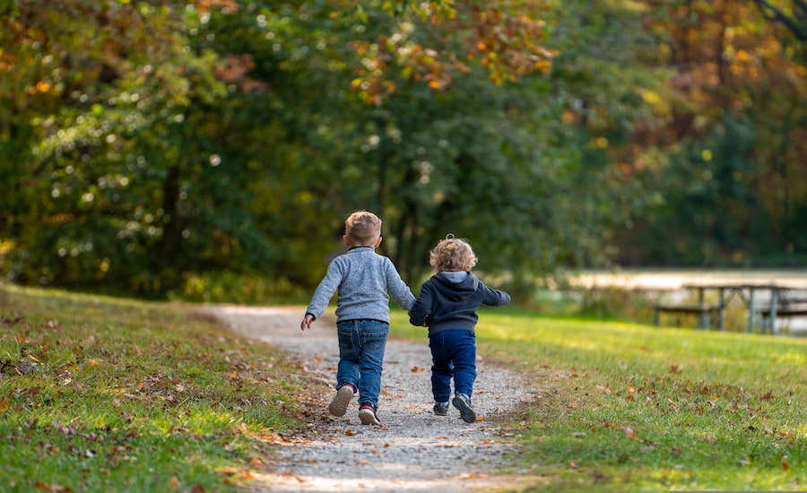 Due bambini che camminano tenendosi per mano lungo un sentiero naturale durante un'escursione all'aperto
